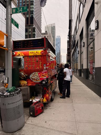 A food truck on a city street with people ordering food.