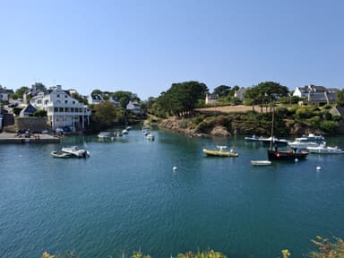 A serene harbor scene with boats and lush greenery under a clear blue sky.