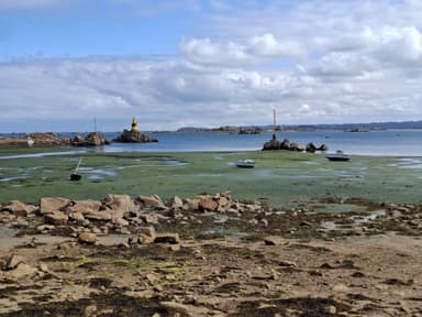 Un paysage côtier avec des bateaux et un phare à l'horizon.